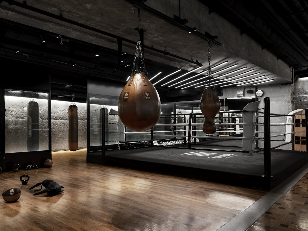 Boxing and MMA ring with heavy bags in a dark training gym